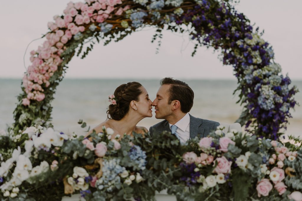 Bride and groom in floral sweethearts table. Jardin del Mar Wedding in Riviera Maya, Mexico. Caro Navarro Photography