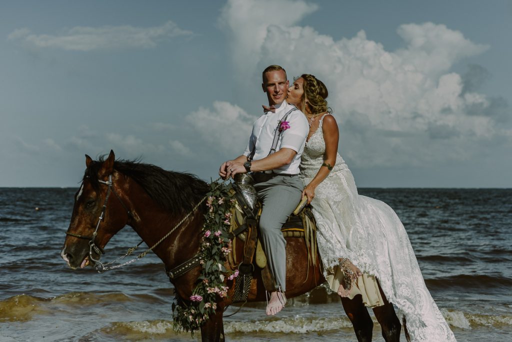 Bride and groom beach portraits on horse at Now Sapphire Riviera Cancun. Caro Navarro Photography