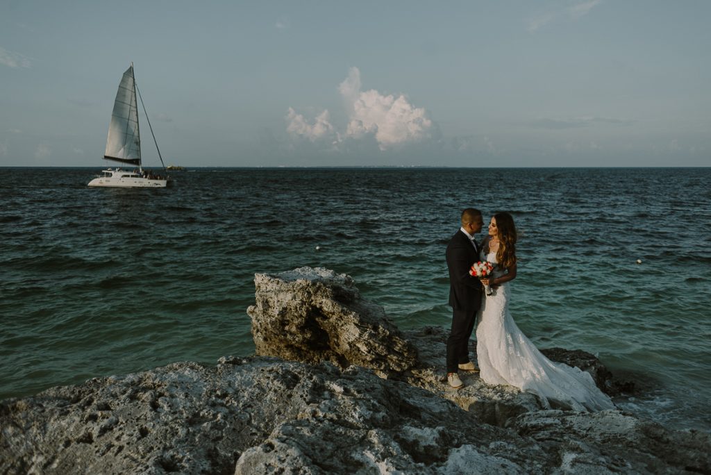 Bride and groom beach portraits with sailboat. Riu Caribe wedding by Caro Navarro Photography