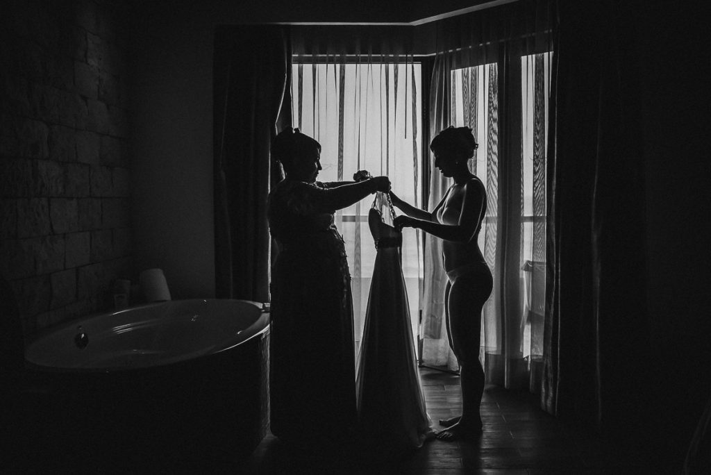 Black and white photo of bride getting into her dress at Hard Rock Riviera Maya Wedding. Caro Navarro Photography