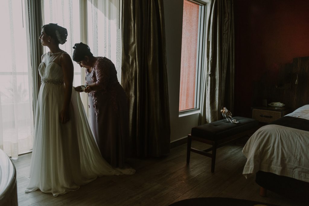 Mother of the bride helping daughter dress. Glam Hard Rock Riviera Maya Destination Wedding by Caro Navarro Photography