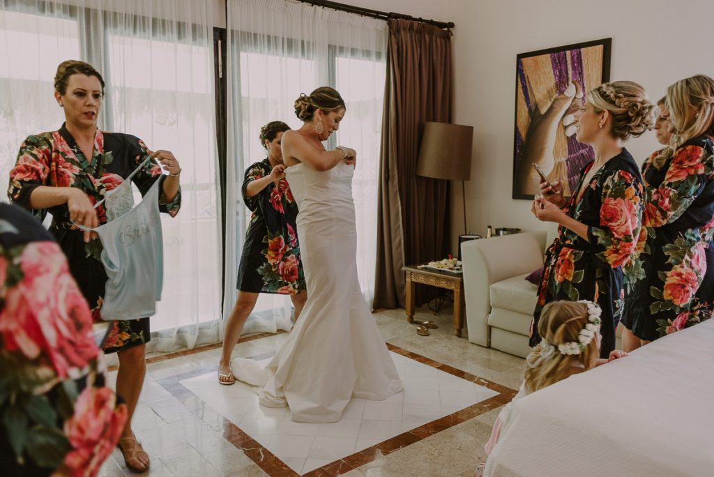 Bride fitting into her wedding dress at Grand Palladium Riviera Maya LGBT Wedding in Mexico. Caro Navarro Photography