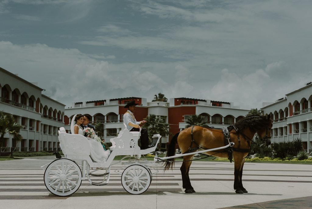 Bride and groom on white horse carriage at Hard Rock Riviera Maya. Caro Navarro Wedding Photography