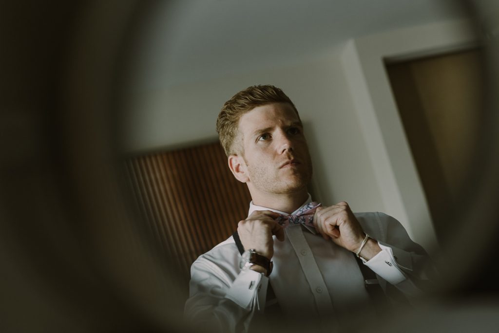 Groom fixing bow tie at Royalton Riviera Cancun Wedding by Caro Navarro Photography 